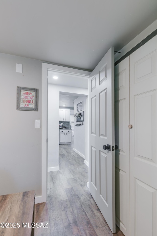 hall with light wood-style floors and baseboards