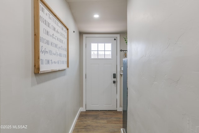 doorway featuring baseboards and wood finished floors