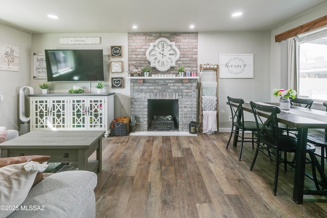 living room featuring a brick fireplace, wood finished floors, and recessed lighting