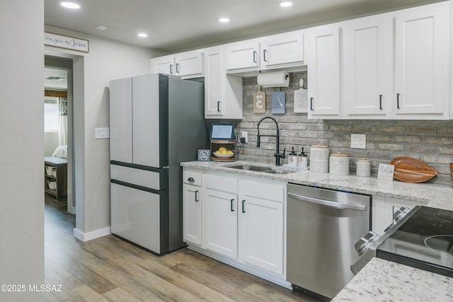 kitchen featuring white cabinets, light wood-style floors, stainless steel appliances, and a sink