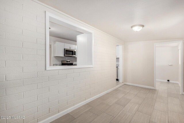 spare room with baseboards and brick wall