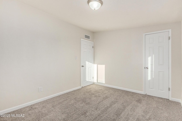 spare room featuring carpet floors, visible vents, and baseboards