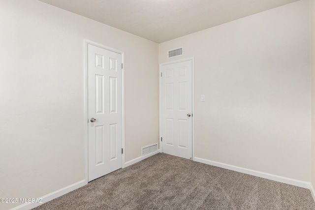 unfurnished room with carpet floors, visible vents, and baseboards