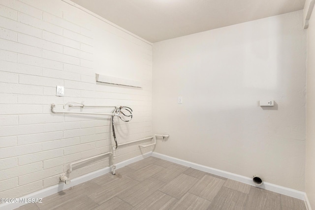 laundry area with brick wall, laundry area, hookup for a washing machine, and baseboards