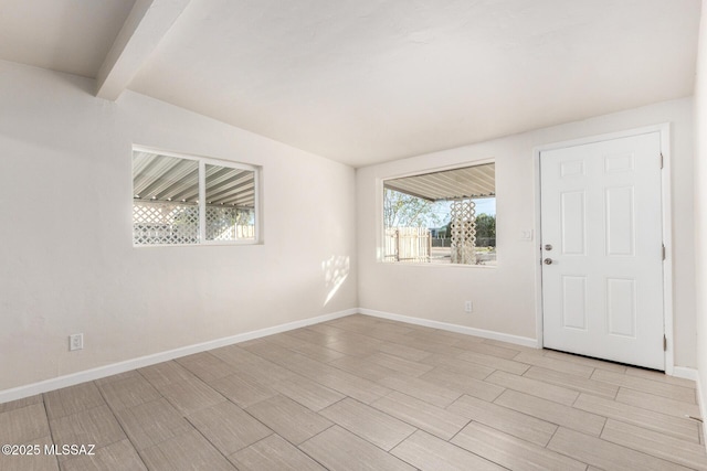 spare room with lofted ceiling with beams, wood tiled floor, and baseboards