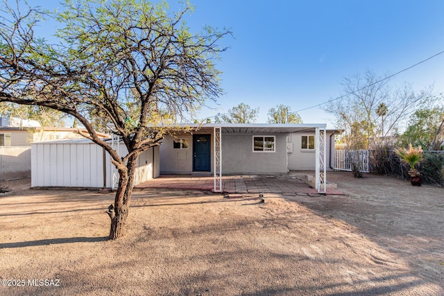 view of front of home featuring fence, a patio, and stucco siding