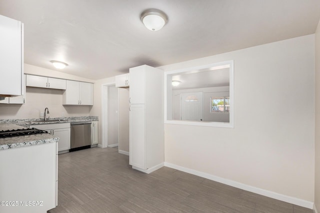 kitchen with light countertops, white cabinets, a sink, dishwasher, and baseboards