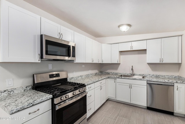 kitchen featuring appliances with stainless steel finishes, white cabinets, and a sink