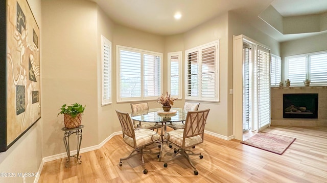 dining area featuring recessed lighting, a fireplace with raised hearth, baseboards, and wood finished floors