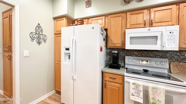 kitchen featuring white appliances, baseboards, light countertops, light wood-style floors, and backsplash