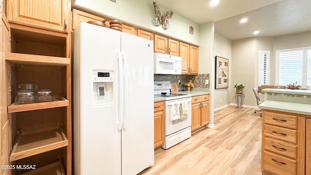 kitchen with light brown cabinets, white appliances, light countertops, light wood-type flooring, and tasteful backsplash