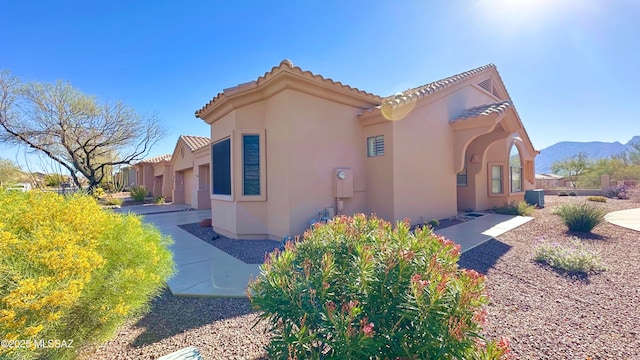 view of home's exterior featuring a tiled roof, a mountain view, and stucco siding