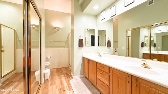 full bathroom with toilet, wood finished floors, a sink, visible vents, and a shower stall