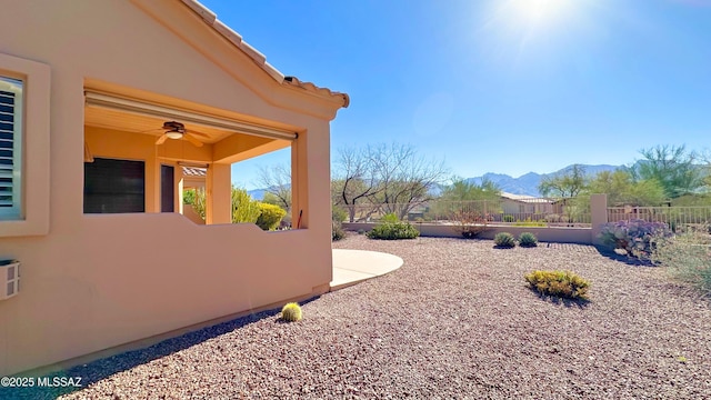 view of yard with a mountain view, fence, and ceiling fan