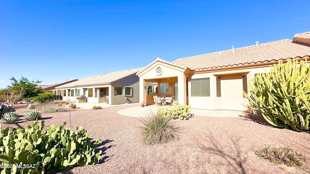 rear view of house with a patio area, a tiled roof, and stucco siding