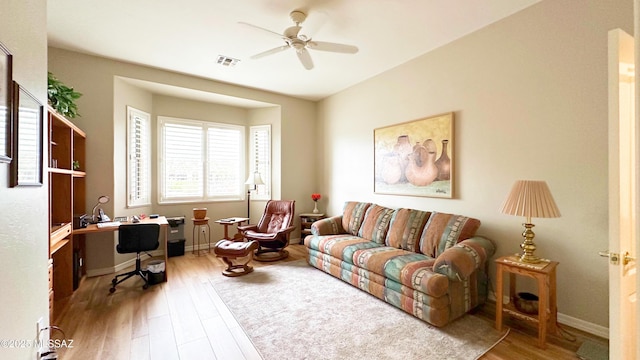 living area with visible vents, ceiling fan, baseboards, and wood finished floors