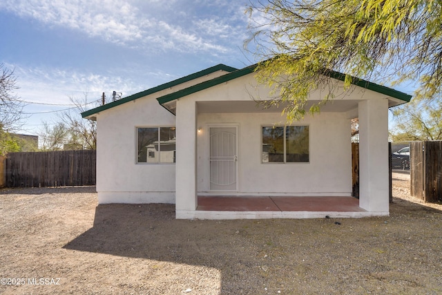 view of front facade featuring a patio area, fence, and stucco siding