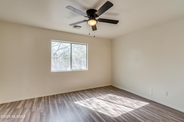 spare room with a ceiling fan, wood finished floors, visible vents, and baseboards