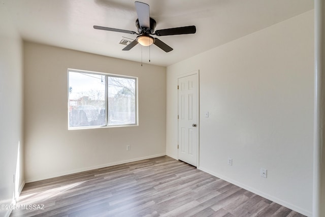 empty room with a ceiling fan, baseboards, visible vents, and wood finished floors