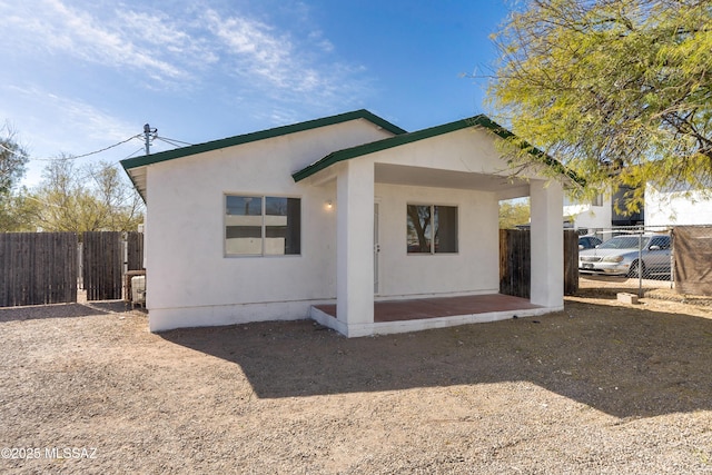 view of front of house featuring a patio, fence, and stucco siding