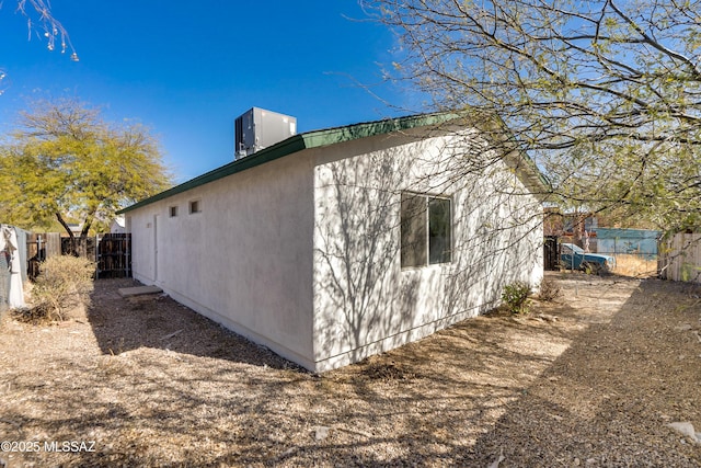 view of home's exterior featuring stucco siding, fence, and central air condition unit