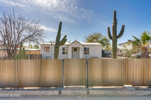 bungalow with a fenced front yard and stucco siding