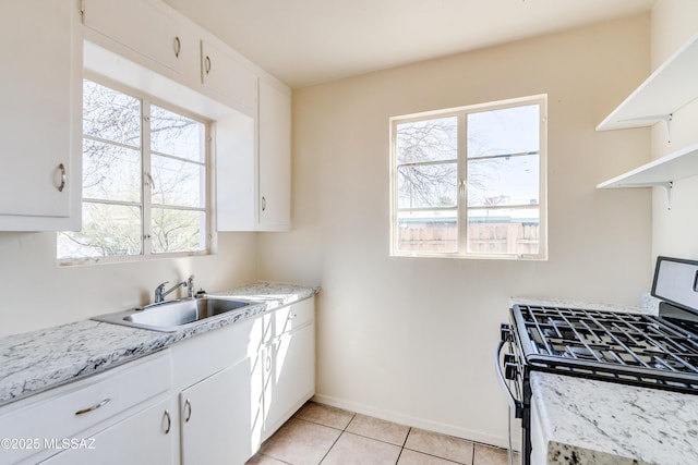 kitchen featuring a healthy amount of sunlight, stainless steel range with gas stovetop, a sink, and light tile patterned flooring