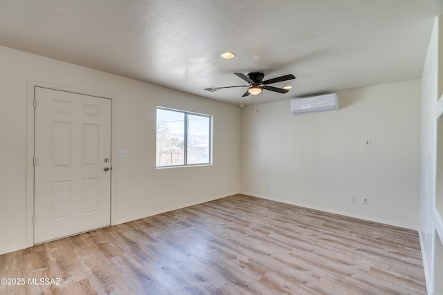 unfurnished room with baseboards, visible vents, a ceiling fan, light wood-style flooring, and a wall mounted AC