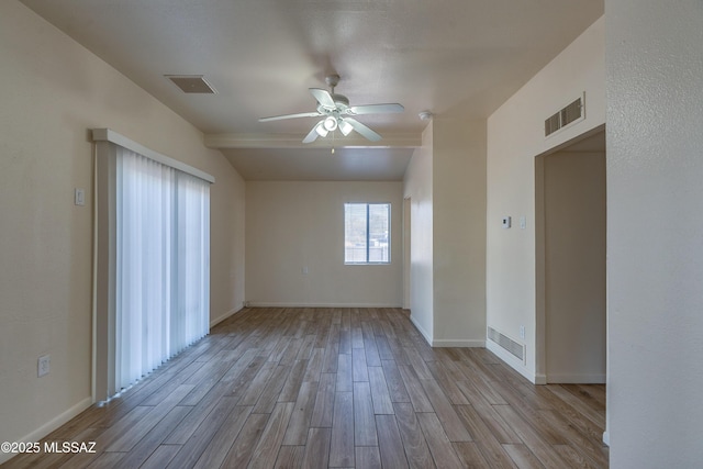 unfurnished room with ceiling fan, visible vents, vaulted ceiling, and wood finished floors