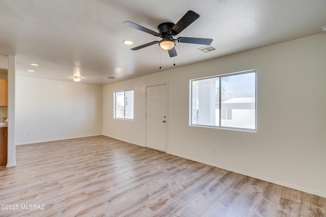 interior space featuring visible vents, ceiling fan, light wood-style flooring, and baseboards