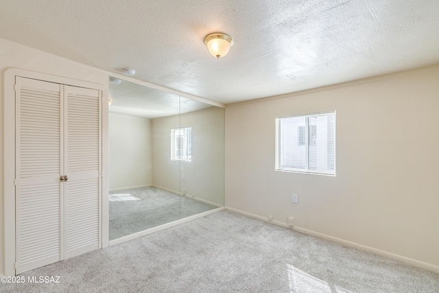 unfurnished bedroom with a textured ceiling, carpet, and baseboards