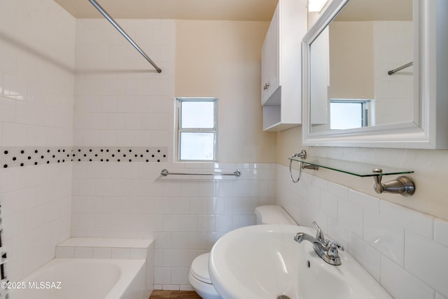 full bath featuring tile walls, toilet, a bathing tub, a sink, and walk in shower