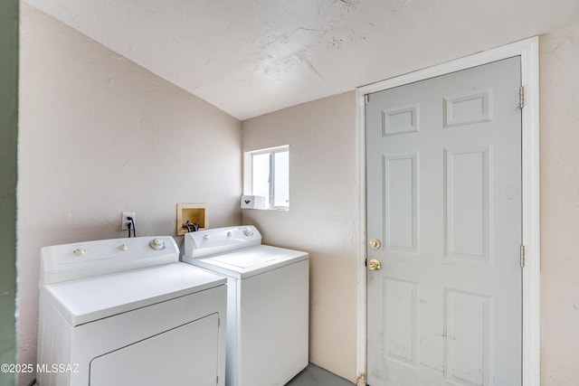 washroom with a textured wall, laundry area, and independent washer and dryer