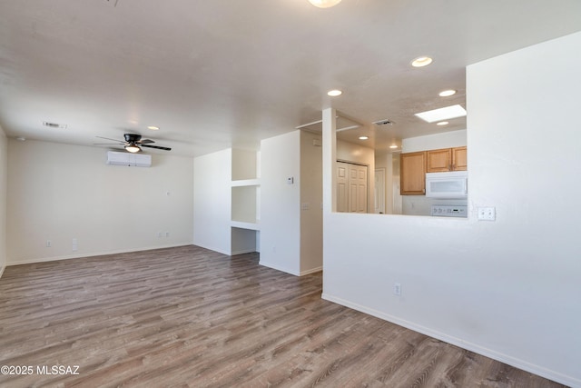 spare room with visible vents, a ceiling fan, a wall unit AC, wood finished floors, and recessed lighting