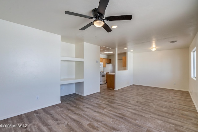 unfurnished living room with ceiling fan, visible vents, baseboards, and wood finished floors