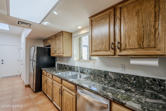 kitchen with light tile patterned floors, stainless steel appliances, a sink, visible vents, and dark stone counters