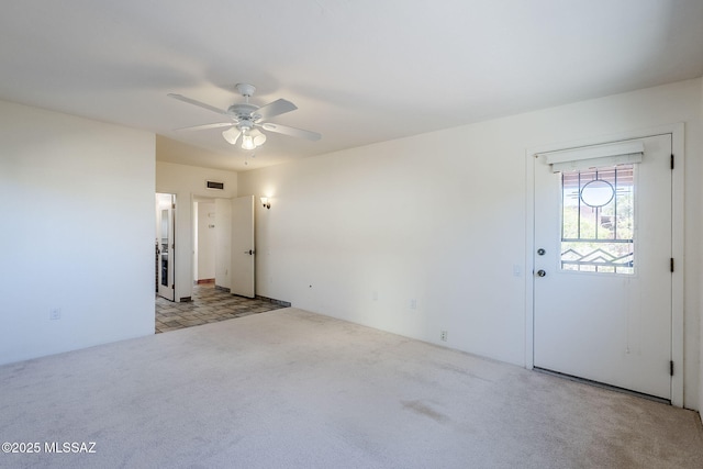 carpeted empty room featuring visible vents and ceiling fan