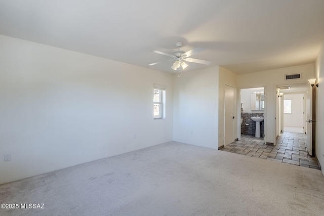 interior space featuring light colored carpet, visible vents, ceiling fan, and a sink