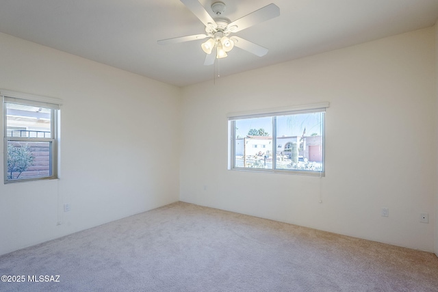 carpeted spare room featuring ceiling fan and a healthy amount of sunlight