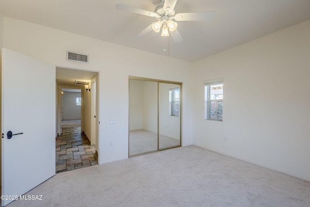 unfurnished bedroom featuring carpet floors, a closet, visible vents, and a ceiling fan