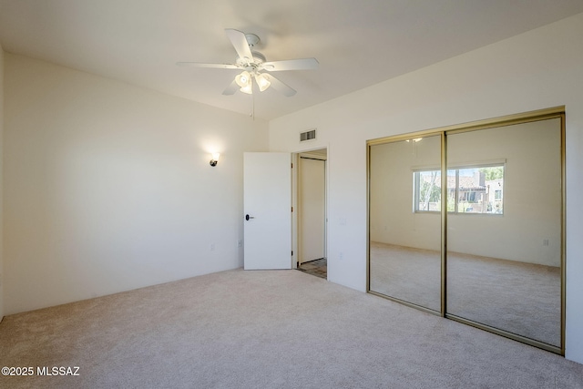 unfurnished bedroom with a closet, carpet, visible vents, and a ceiling fan