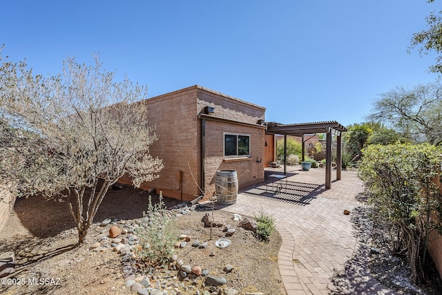 view of home's exterior with a patio, brick siding, and a pergola