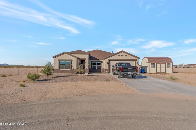 view of front of home with a garage, concrete driveway, an outbuilding, a shed, and stucco siding