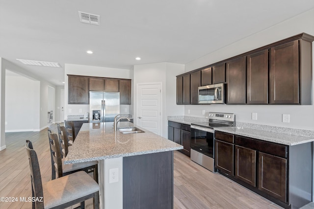 kitchen with stainless steel appliances, visible vents, a sink, and dark brown cabinets