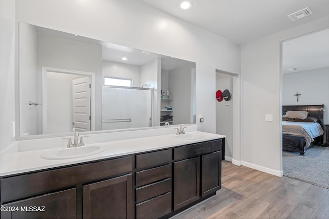 bathroom featuring visible vents, a sink, ensuite bath, and wood finished floors