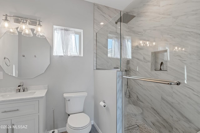 full bath with a marble finish shower, baseboards, vanity, and toilet