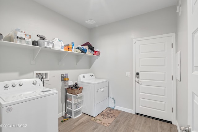 clothes washing area featuring light wood-type flooring, washing machine and dryer, laundry area, and baseboards