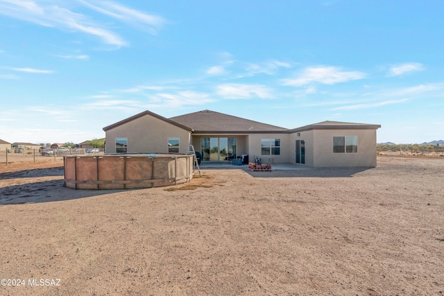 rear view of property featuring a patio area, an outdoor pool, and stucco siding