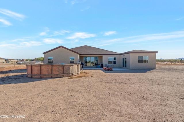 back of property with a patio area, an outdoor pool, and stucco siding