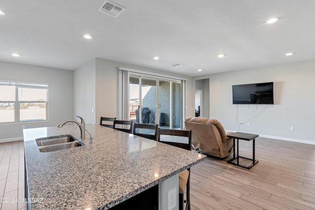 kitchen with plenty of natural light, visible vents, a kitchen breakfast bar, and a sink